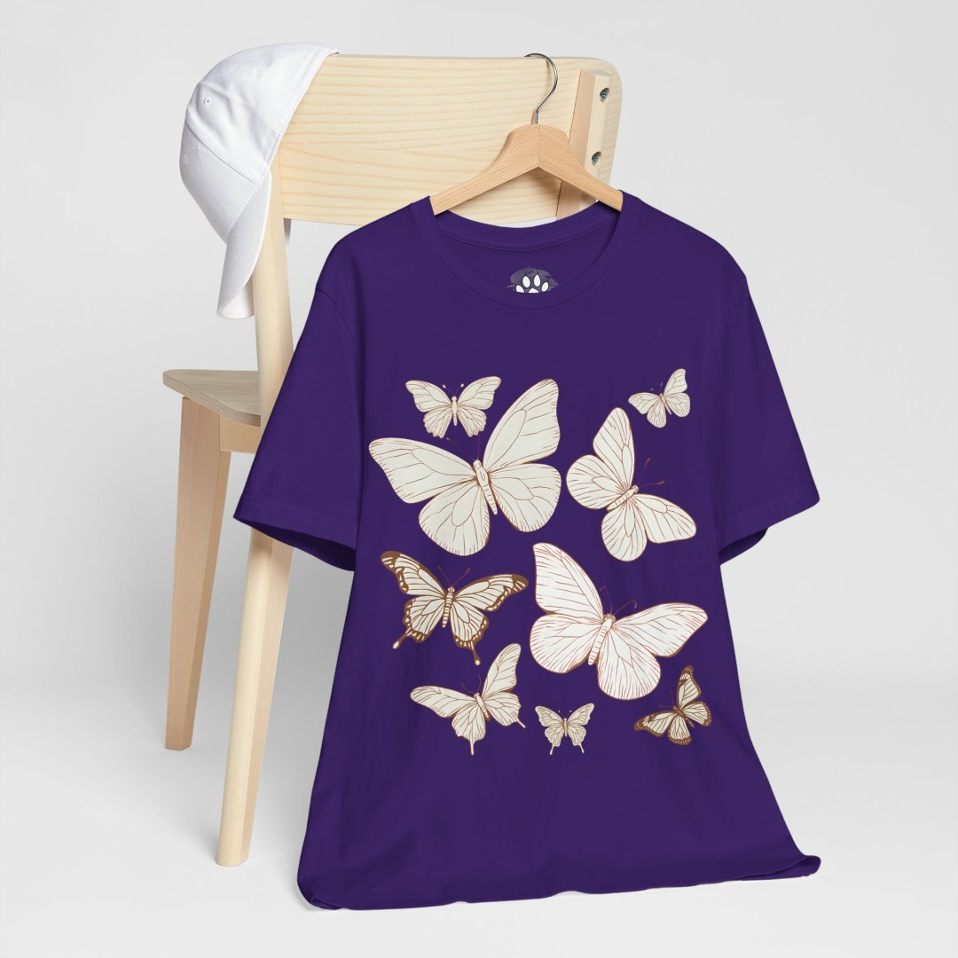 10638849141446300232_2048.jpeg Purple t-shirt with butterfly design hanging on a chair.