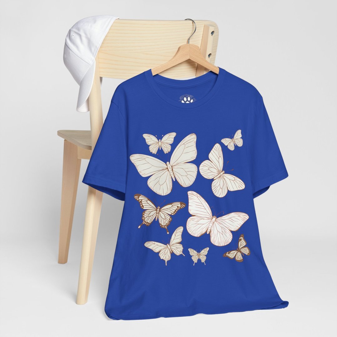 12638898183952853480_2048.jpeg Blue t-shirt with butterfly designs on a wooden chair.