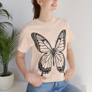 Bella Gatti Tabby Portrait T-shirt Butterfly Graphic Tee. Smiling woman wearing a light peach t-shirt with a large black butterfly design.