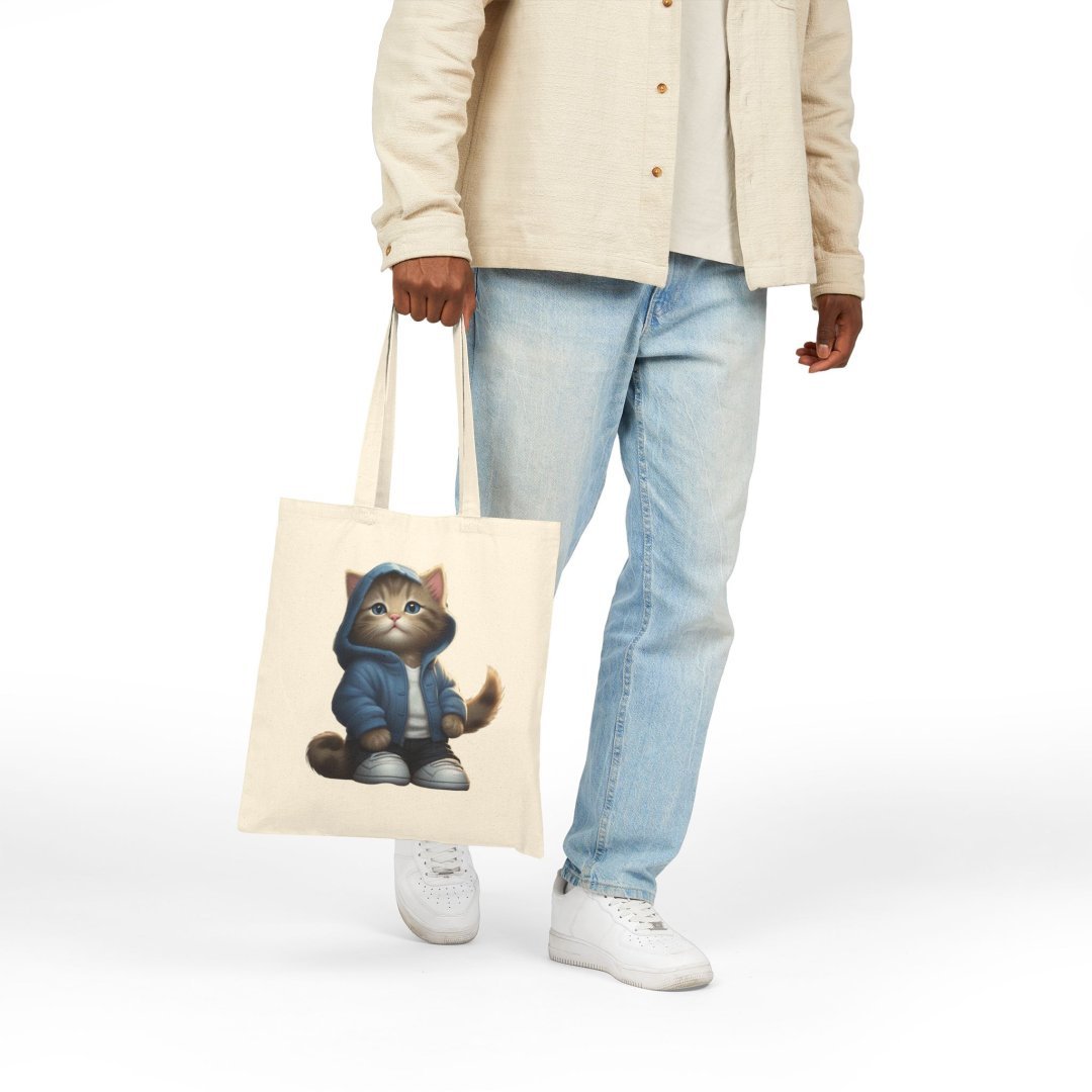 17455252789481219572_2048.jpeg Person holding a tote bag with a cat in a hoodie design.