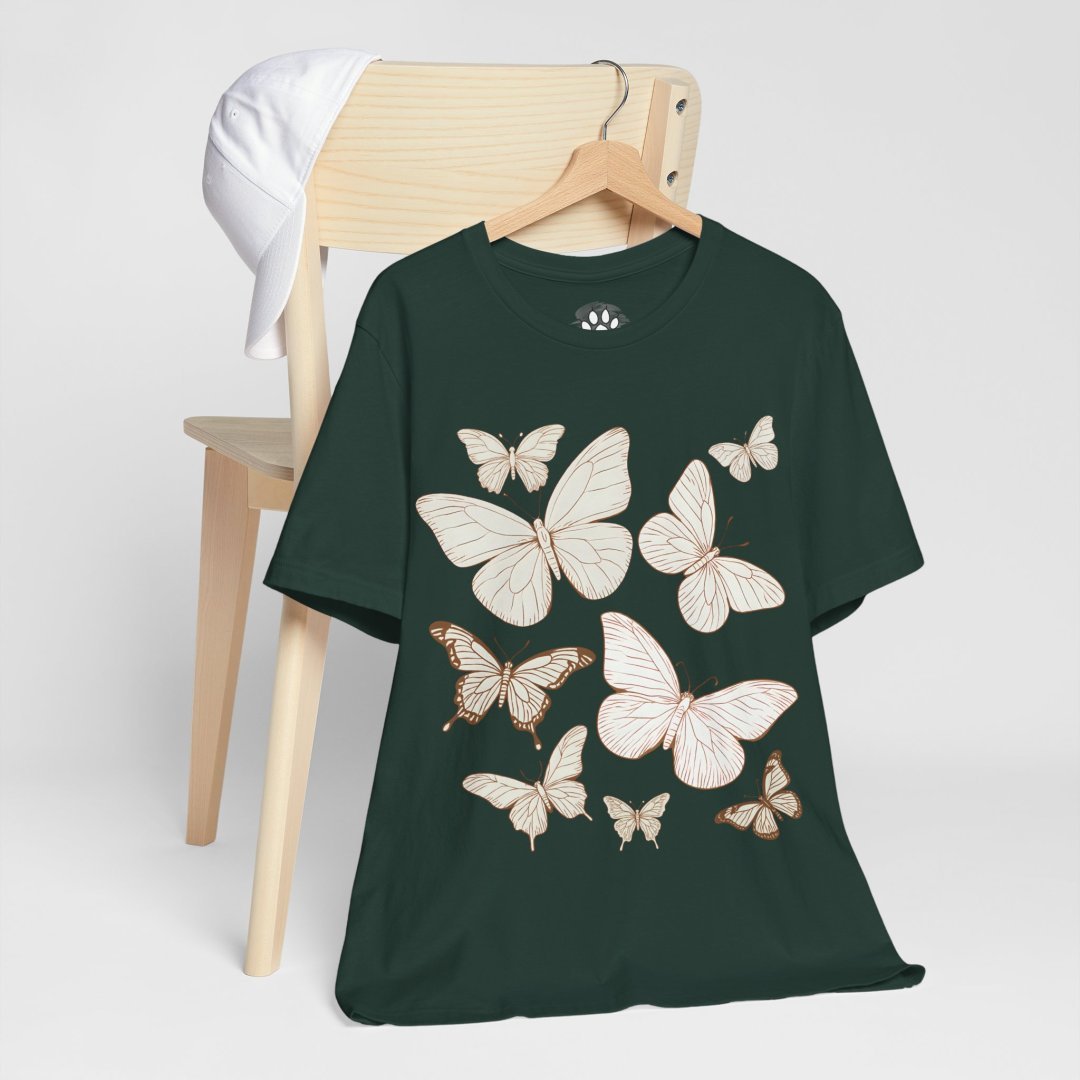17921303970961532980_2048.jpeg Green t-shirt with butterfly illustrations on a chair with a white cap.