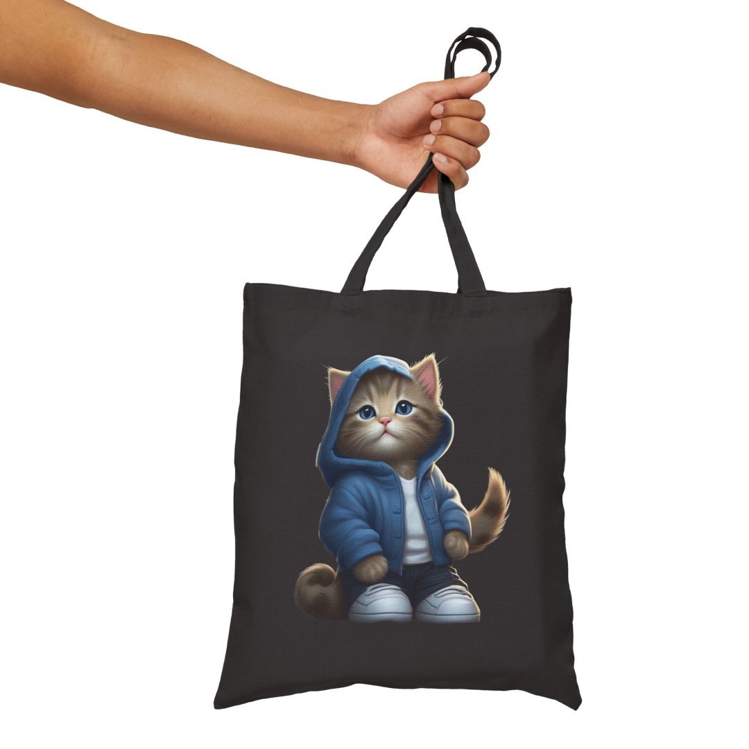 4741758302157021956_2048.jpeg Person holding a black tote bag with a cute cat in a hoodie design.