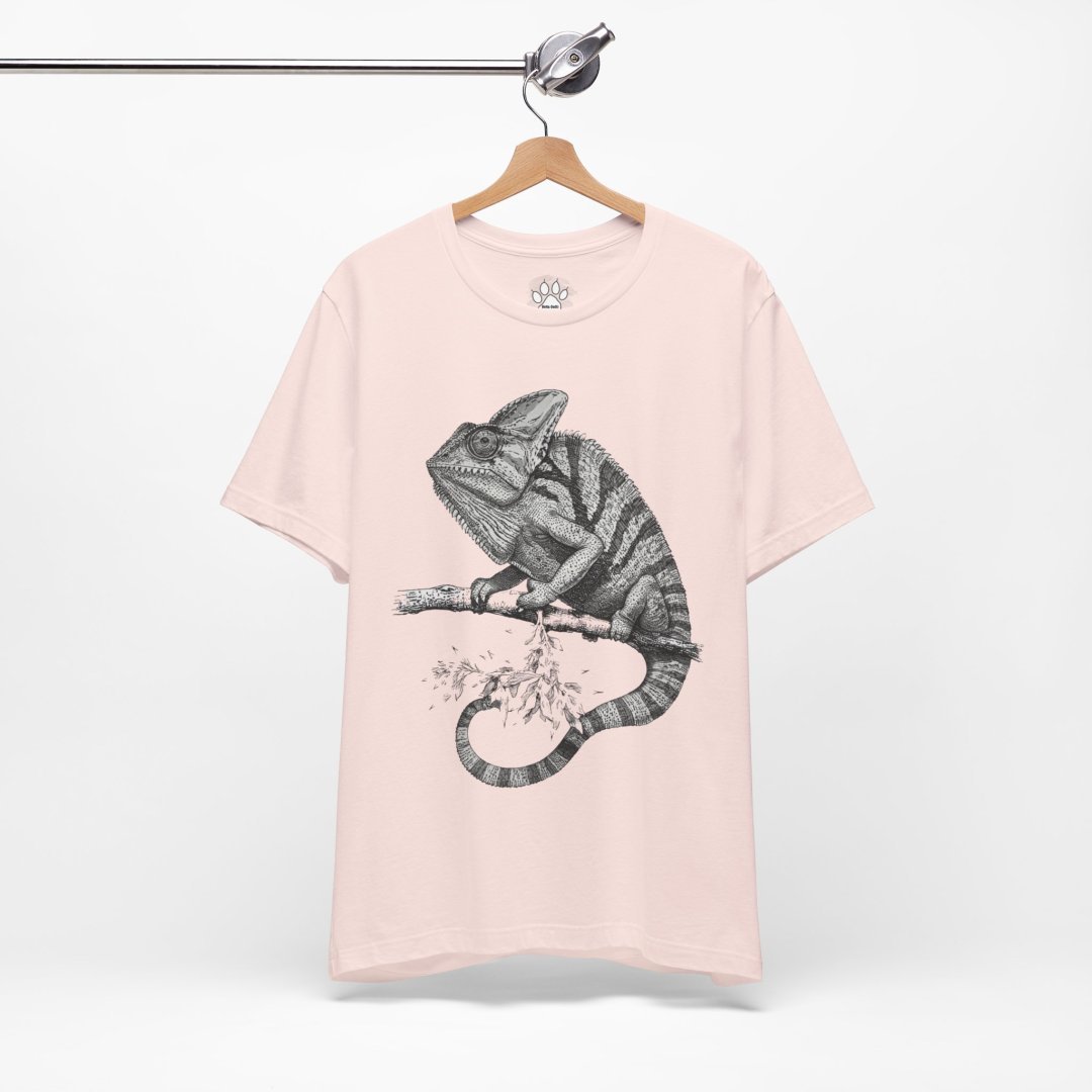 5530565815741631056_2048.jpeg Pink t-shirt with a chameleon illustration hanging on a wooden hanger.
