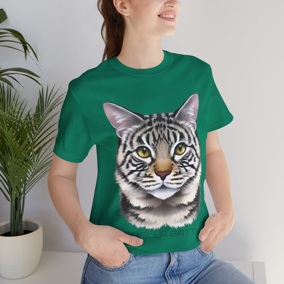 7725759630834184246_2048-3.jpeg Smiling woman wearing a green t-shirt featuring a striped cat's head and "BELLA GATTI" text.