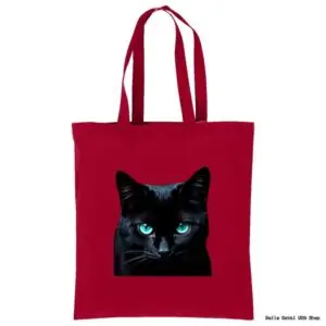 A red tote bag with two handles features a realistic image of a black cat&rsquo;s face with striking bright blue eyes centered on the front. The background is plain white.