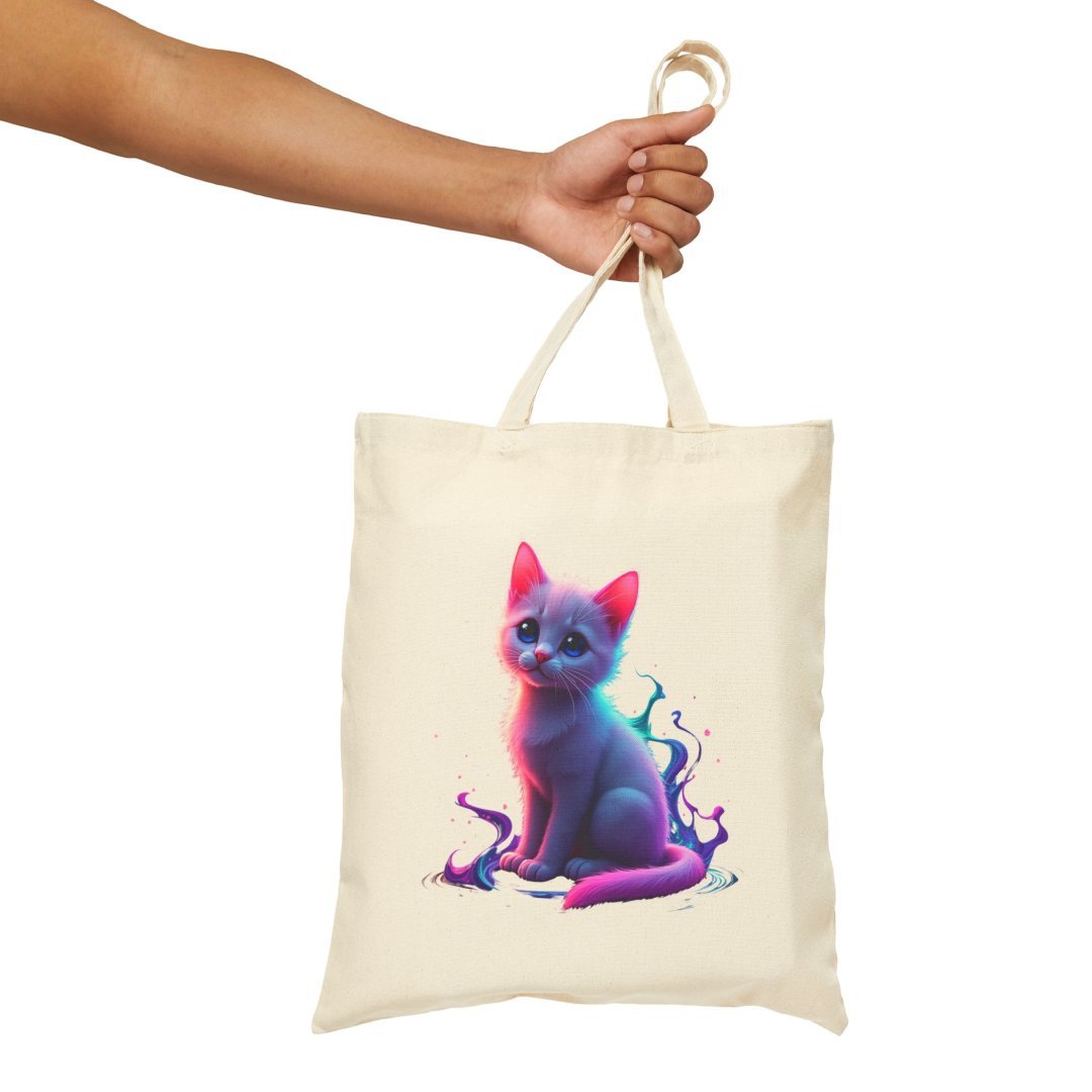 10820593318932001895_2048.jpeg Hand holding a tote bag with a colorful, artistic cat design.