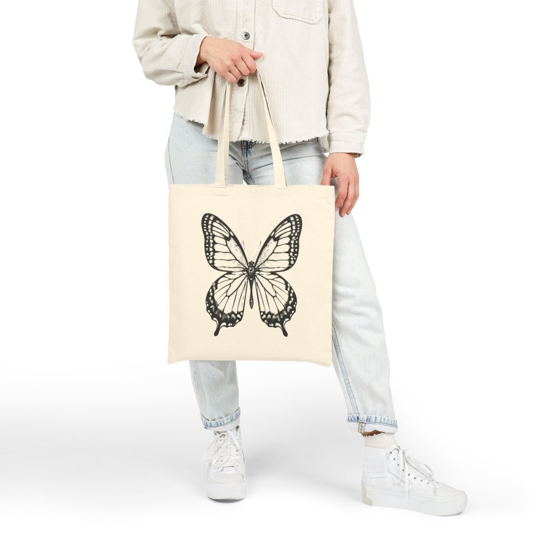 1155613212506166285_2048.jpeg Person holding a tote bag with a butterfly design.