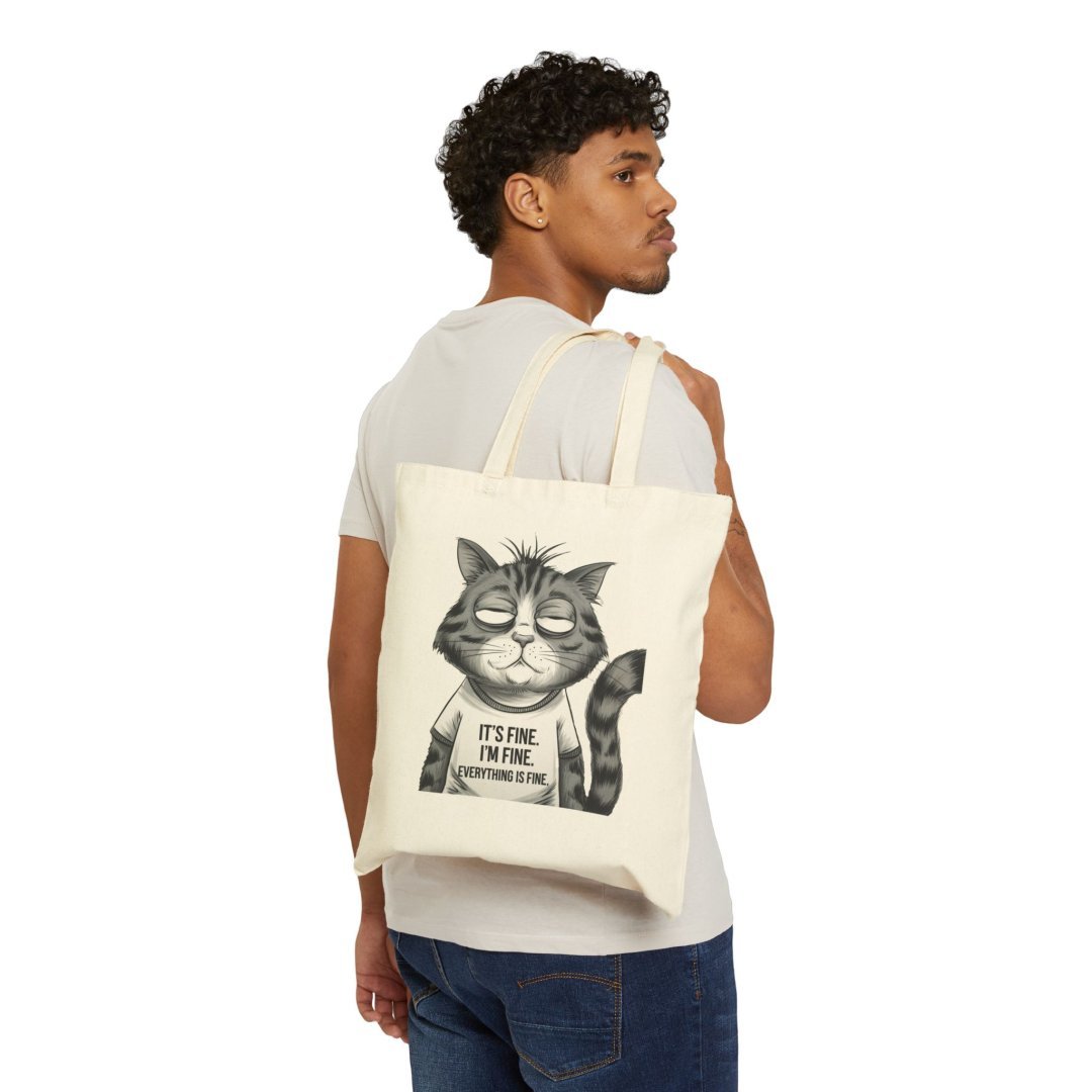 11909033988610228209_2048.jpeg Man carrying a tote bag with a cartoon cat design.