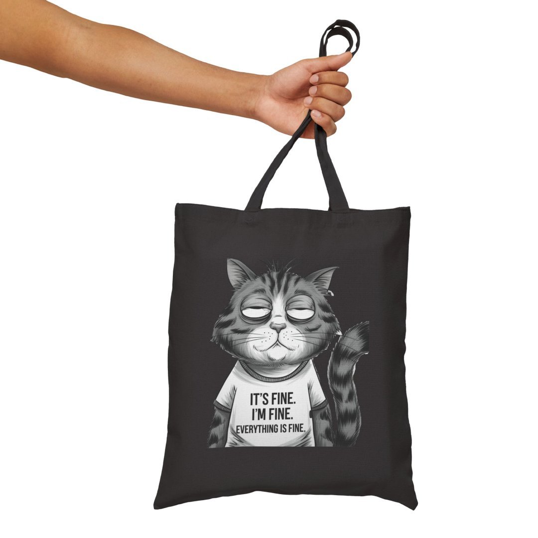 11911090507536708590_2048.jpeg Hand holding a black tote bag with a cartoon cat and text.