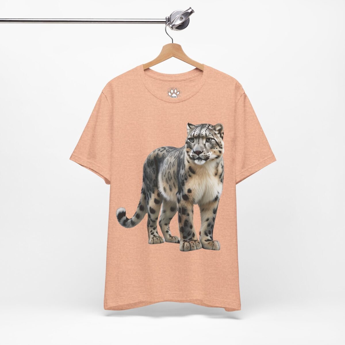 13247415646743746872_2048.jpeg Peach t-shirt with a snow leopard graphic hanging on a hanger.