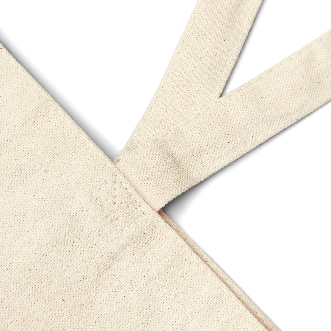 1424390607219495124_2048.jpeg Close-up of a beige canvas tote bag corner and handle.
