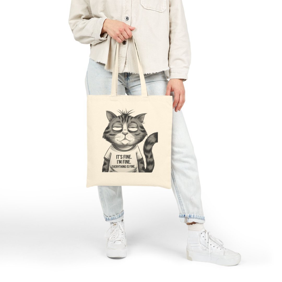 14666871054323980899_2048.jpeg Person holding a tote bag with a cartoon cat and text saying 'It's fine. I'm fine. Everything is fine.'