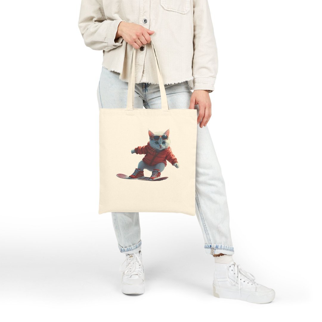 14919398682320746659_2048.jpeg Person holding a tote bag with a cat snowboarding design.