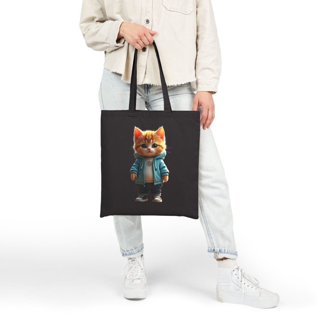 17466492761570602103_2048.jpeg Person holding a black tote bag with a cute cat in a blue jacket design.