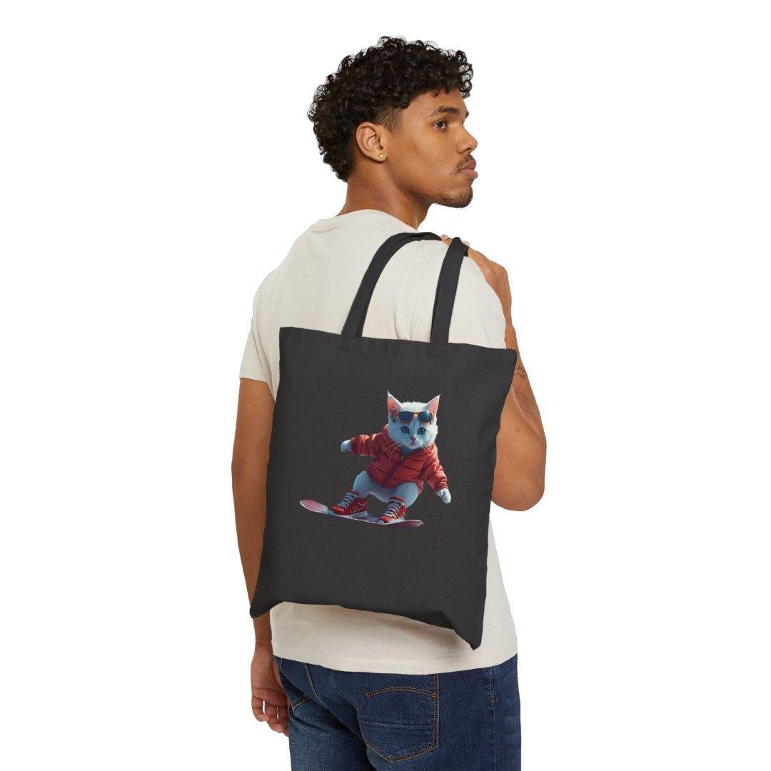 2930727180922303644_2048.jpeg Person holding a tote bag with a cat snowboarding design.
