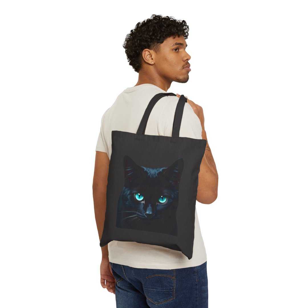 3758033624291030454_2048.jpeg Man holding a black tote bag with a glowing cat face design.