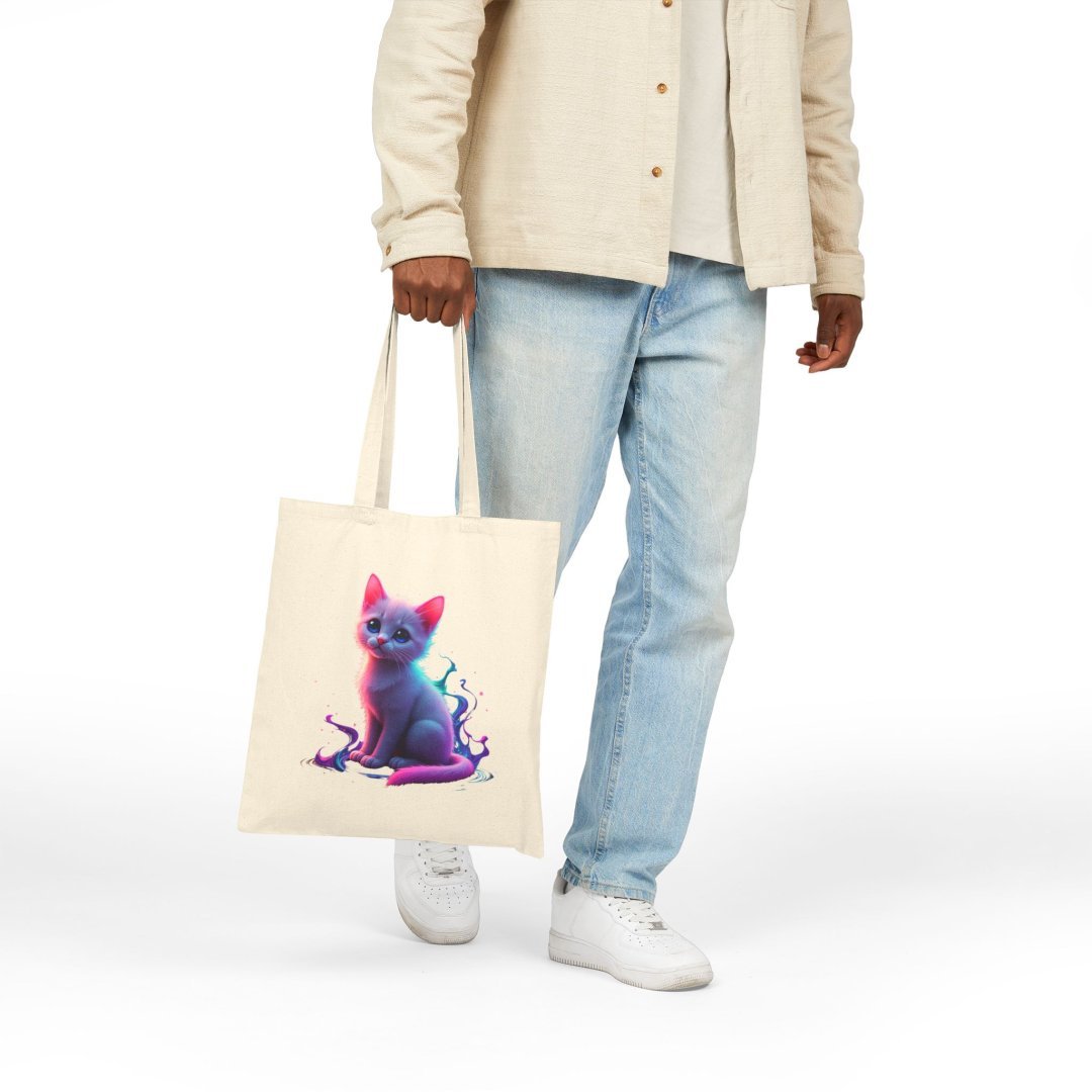 3816107862921693474_2048.jpeg Person holding a tote bag with a colorful cat design.