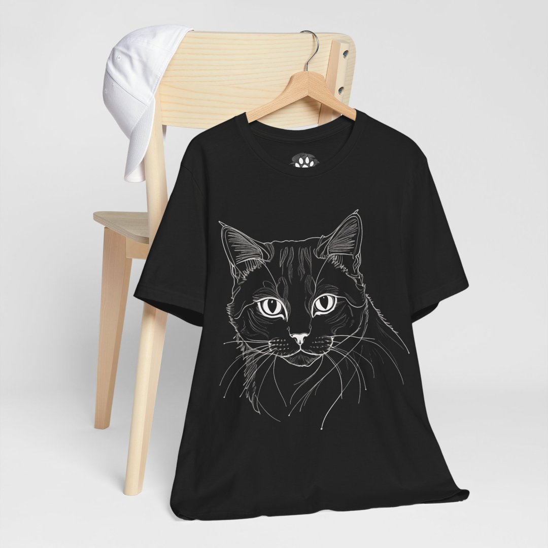 5249022429805347193_2048.jpeg Black t-shirt with a cat illustration hanging on a chair.