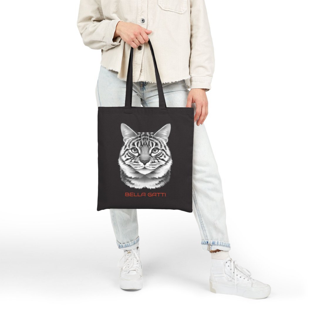 621439168350039546_2048.jpeg Person holding a black tote bag with a cat face design and 'Bella Gatti' text.