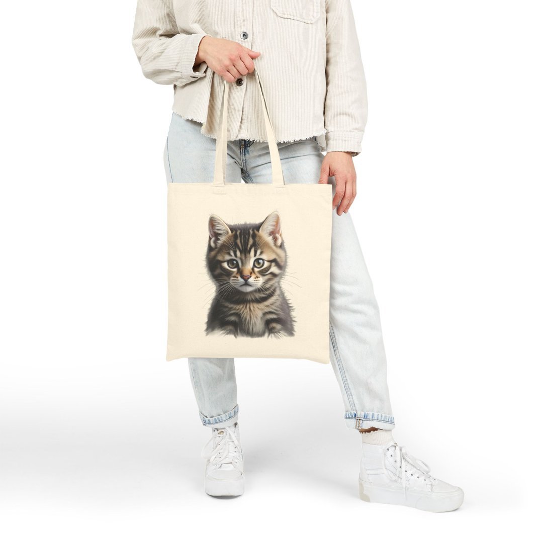 65884220180436813_2048.jpeg Person holding a tote bag with a cute kitten design.