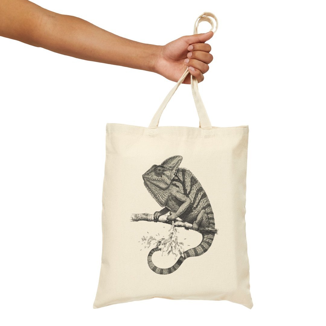 8928136651204347821_2048.jpeg Hand holding a tote bag with a chameleon design.