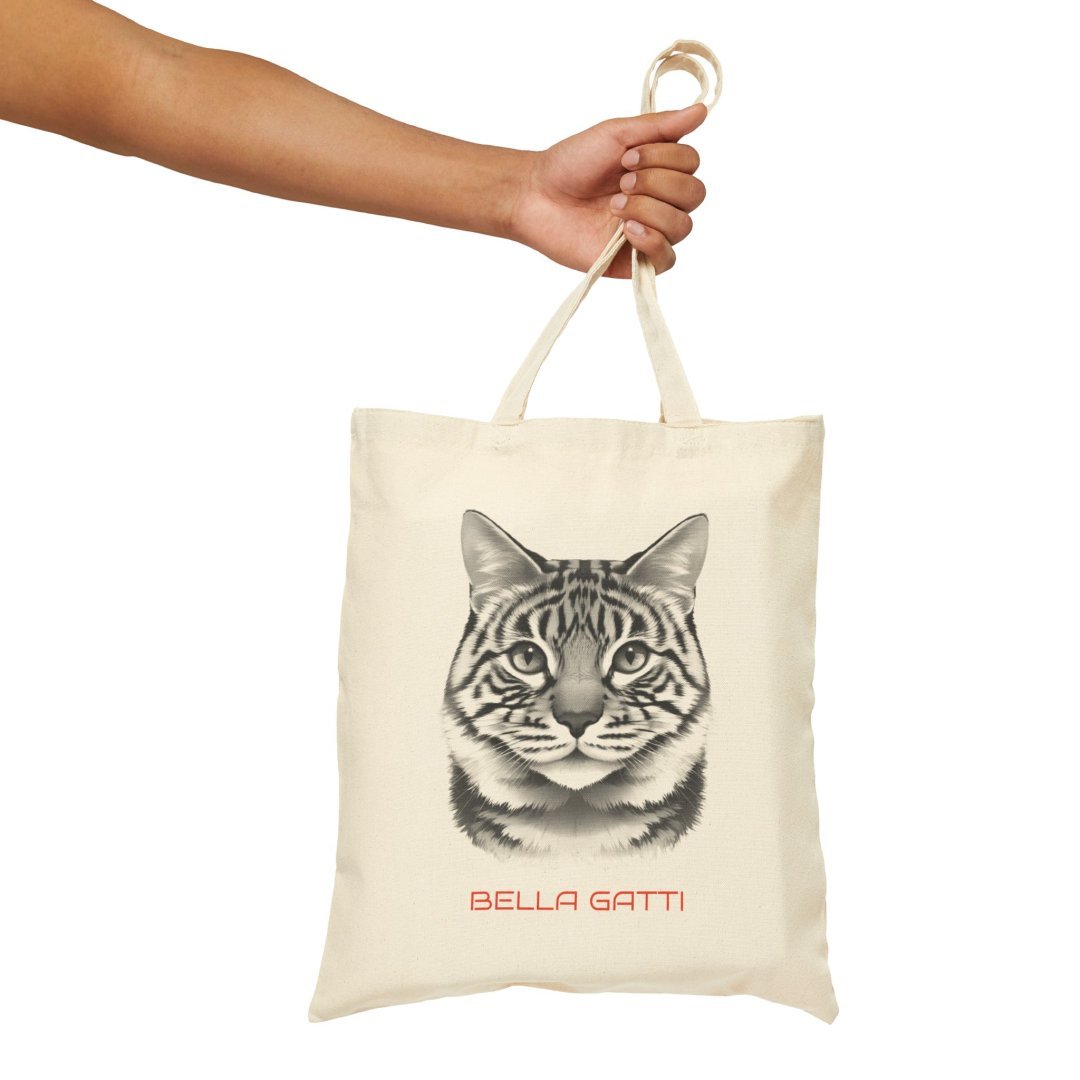 9132999098769646238_2048.jpeg Hand holding a tote bag with a cat face design and 'Bella Gatti' text.