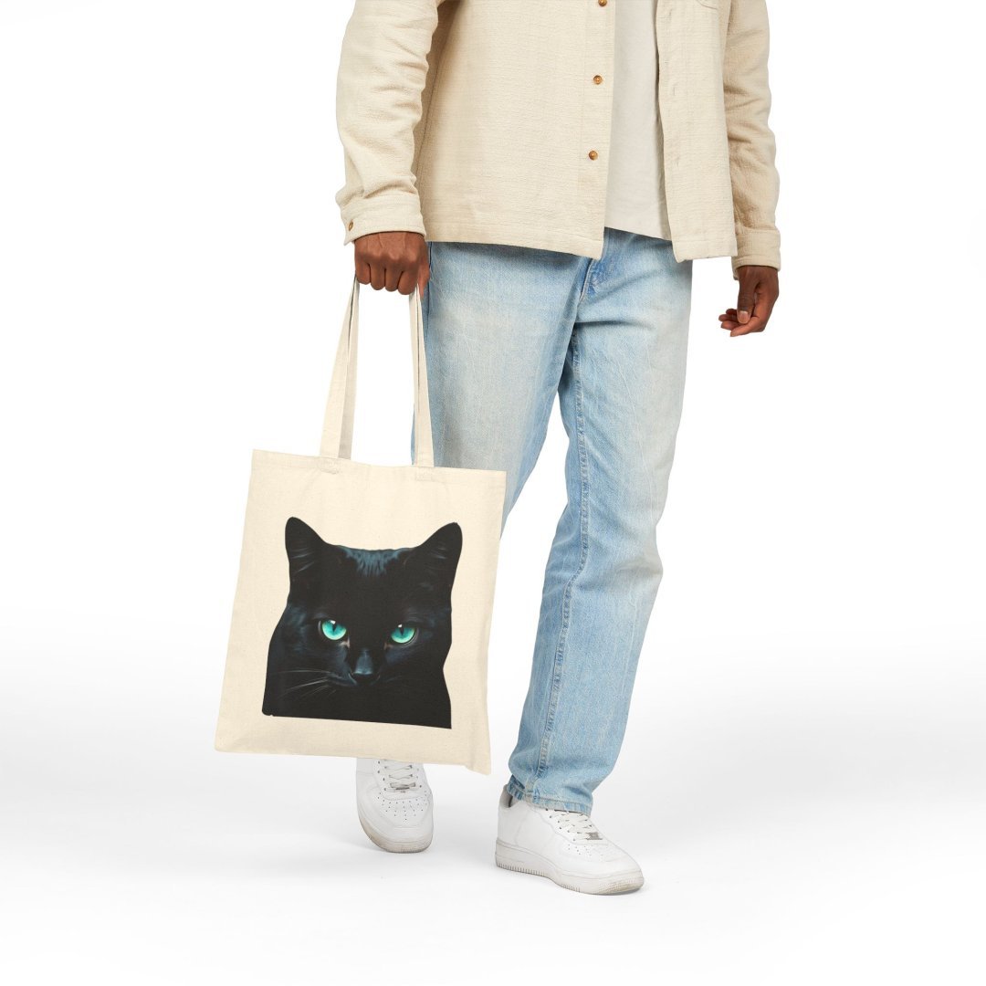 9616869702936797216_2048.jpeg Person holding a tote bag with a black cat design.
